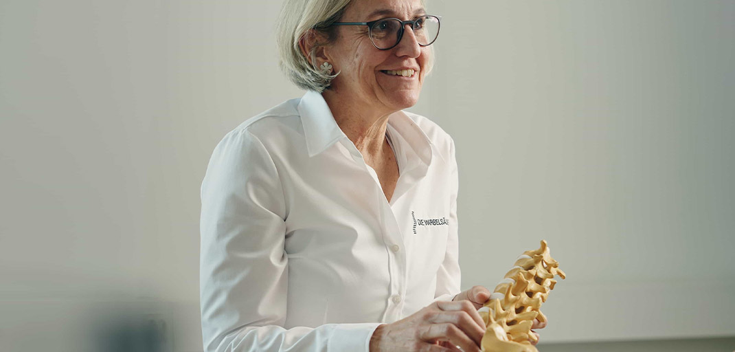 Dr. Kartak mit Modell der Lendenwirbelsäule in der Hand