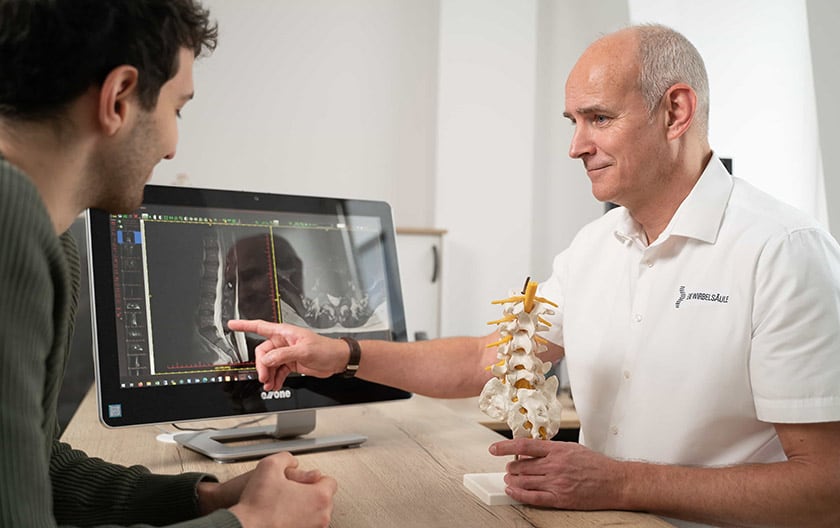 Dr. Wiedenhöfer erläutert Patienten Befund an digitaler Röntgenaufnahme und Modell
